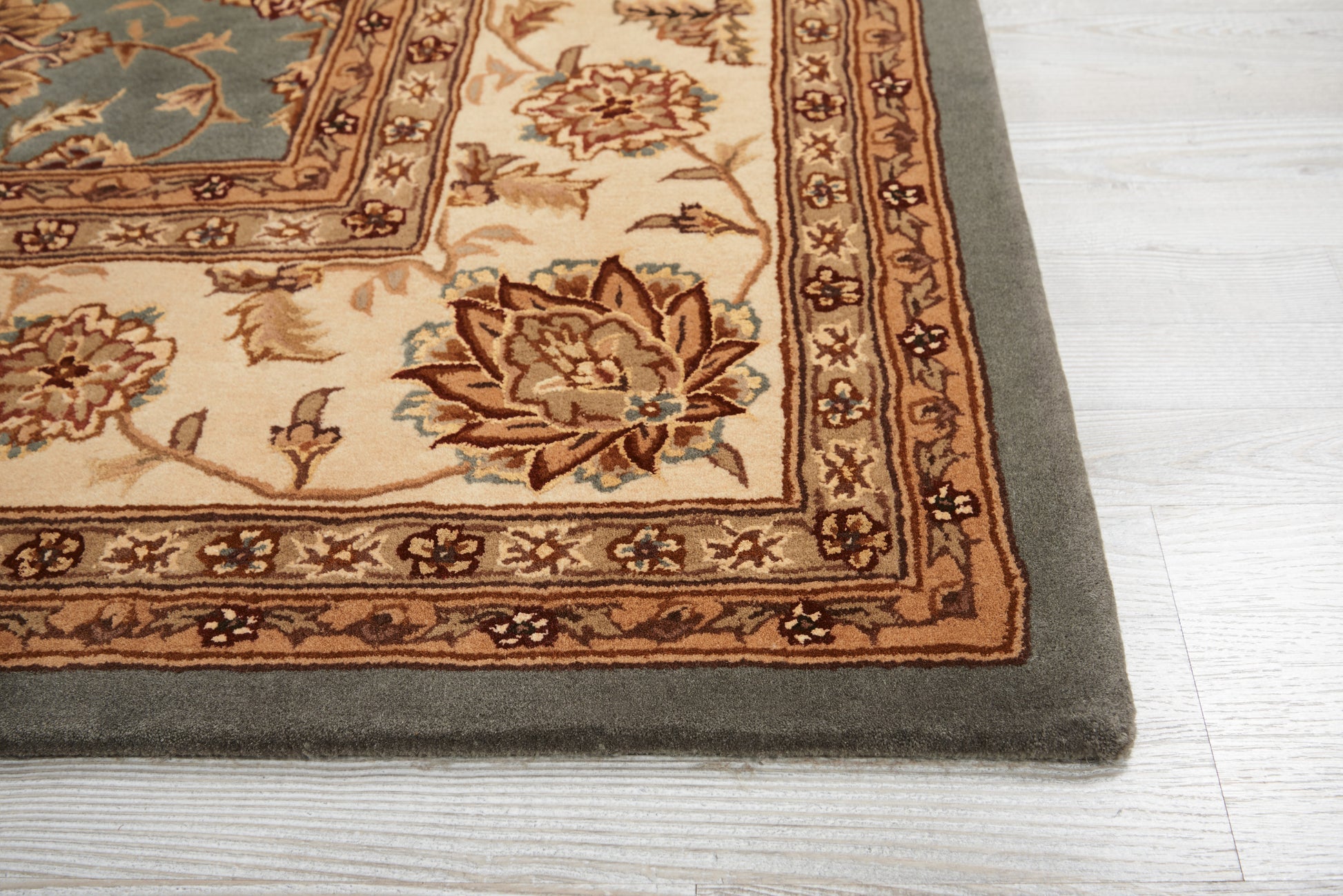 Rectangular beige oriental rug with brown floral border, teal accents, and a dark grey outer edge on light wood floor.