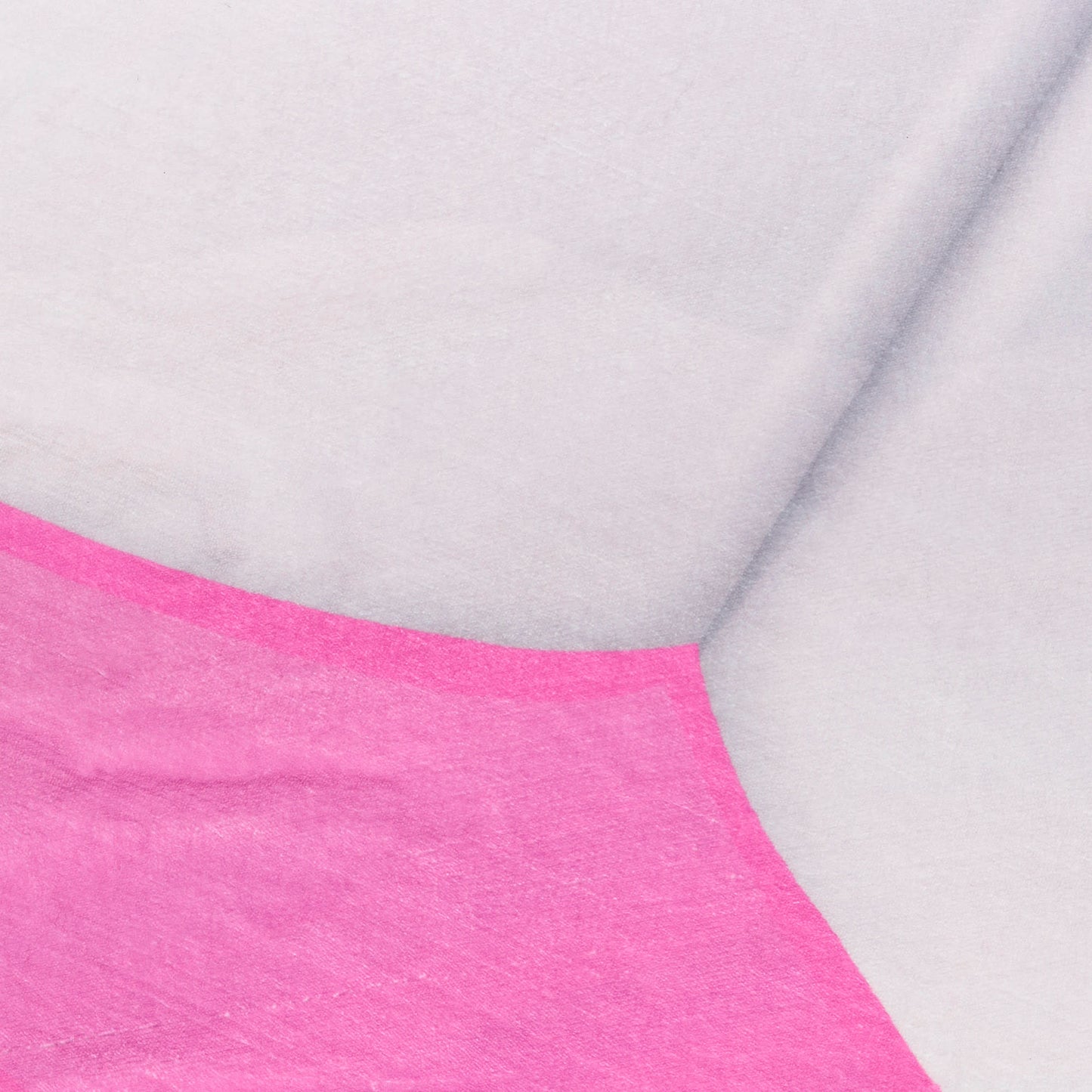 Close-up of bright pink fabric edge against light gray textile with a curved diagonal seam.