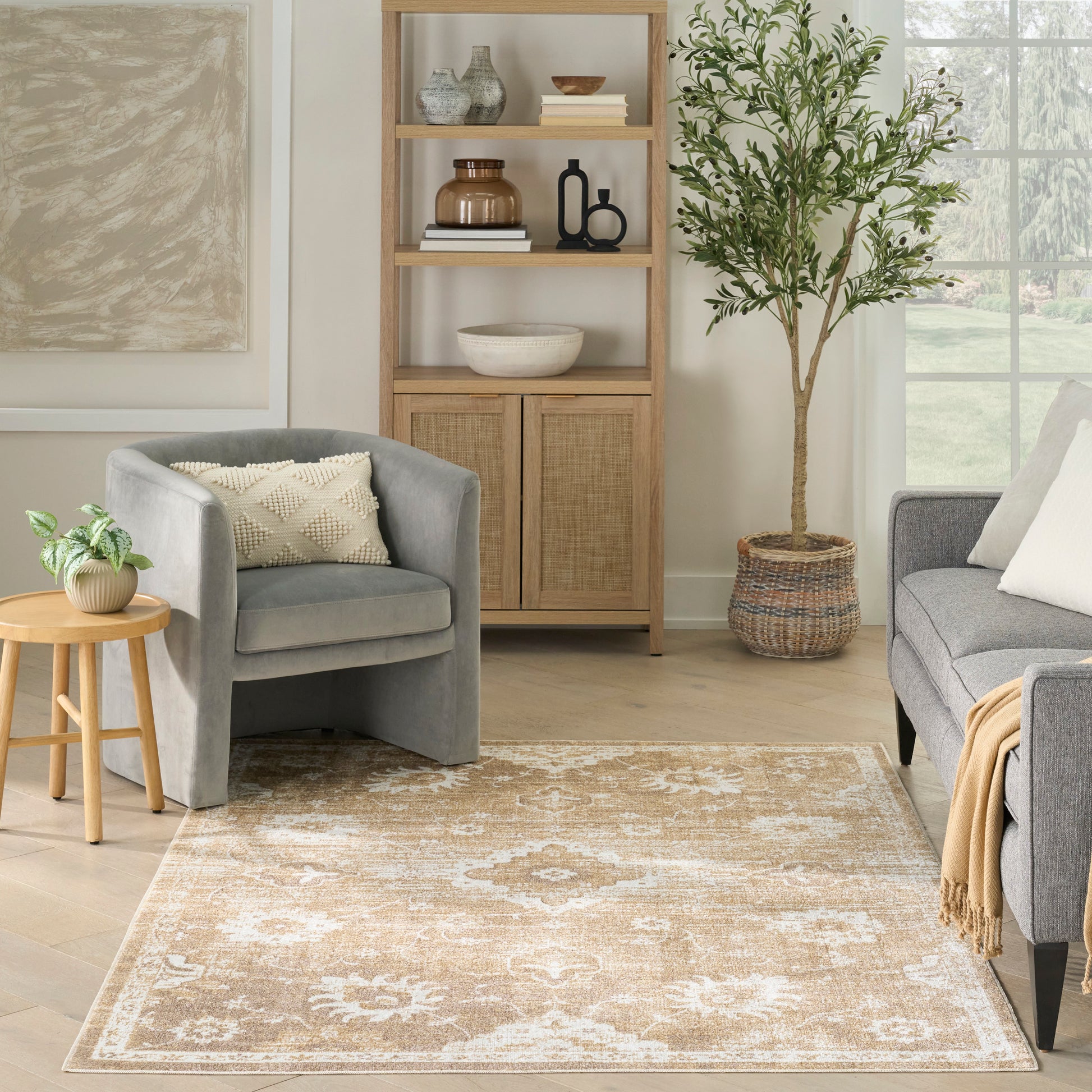 Beige oriental-style area rug with white pattern in a light living room with gray chairs and wooden shelves.
