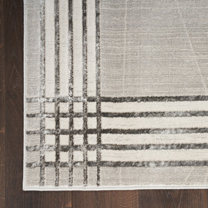 Beige and gray area rug with a bold dark grid pattern on a dark wood floor.