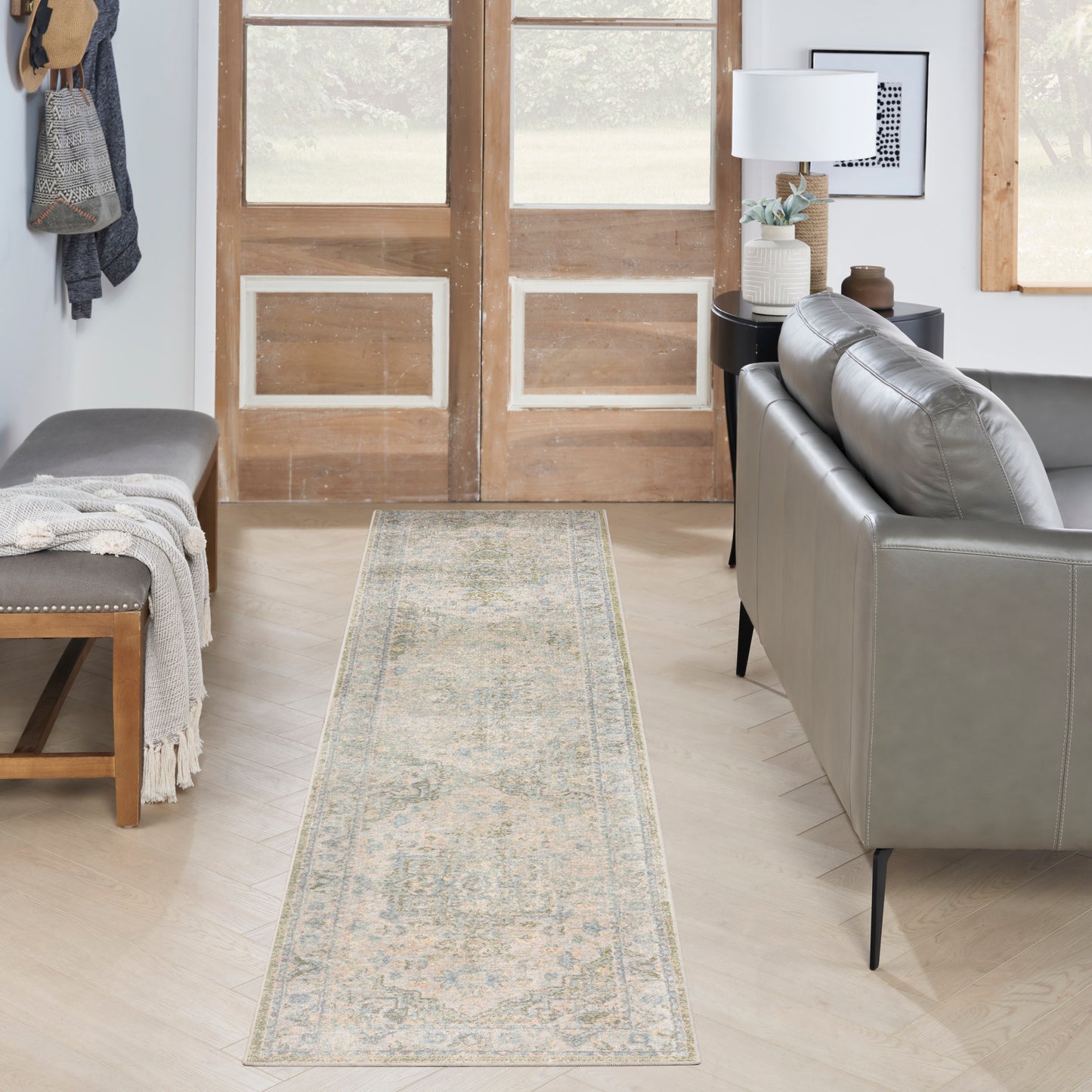Long woven runner rug in light-blue & cream with an ornate pattern in a modern living room with a gray sofa.