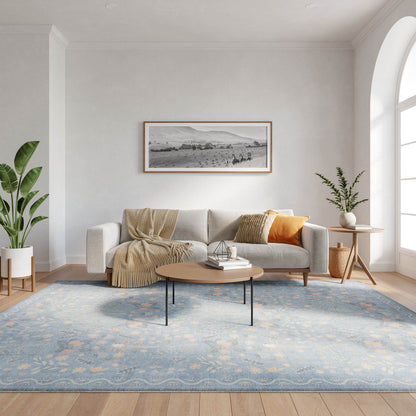 Bright Scandinavian living room with light gray sofa, beige throw, mustard pillow, round wood coffee table, blue area rug, and plants.