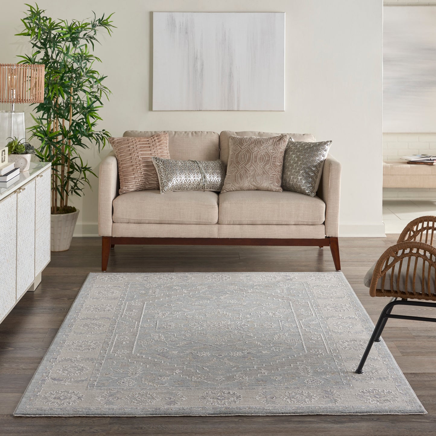 Vintage 5' x 8' rug in light gray with a subtle pattern on the floor, with a potted plant and abstract wall art nearby.