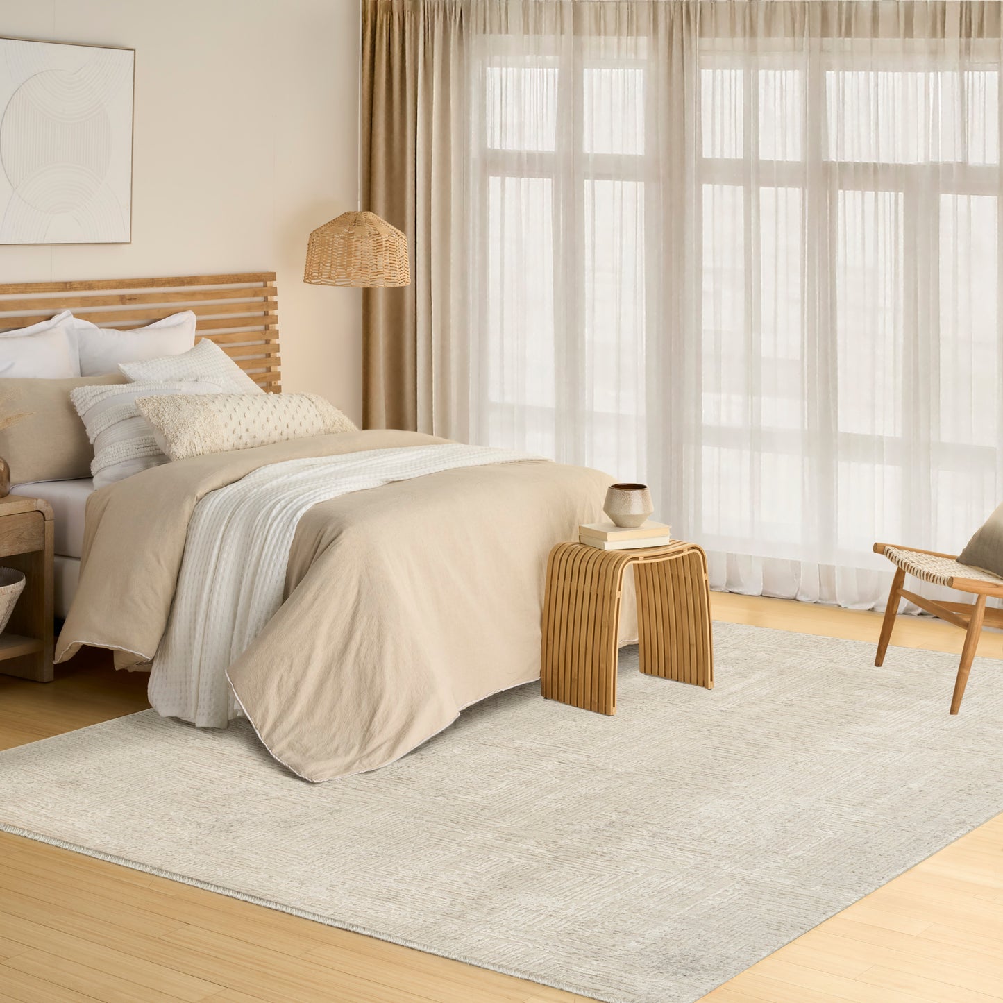 Neutral beige bedroom with a light rug, wooden slatted headboard, layered bedding, woven lamp, and sheer curtains.