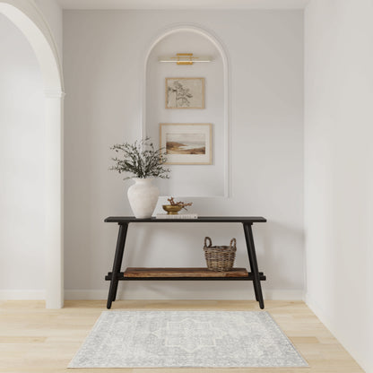 Black two-tier mid-century console in an arched alcove with greenery vase, framed art, basket, and gray patterned rug.
