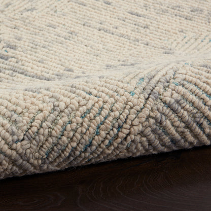 Beige textured loop rug with subtle teal flecks on dark wood floor, chunky soft pile, cozy contemporary style.