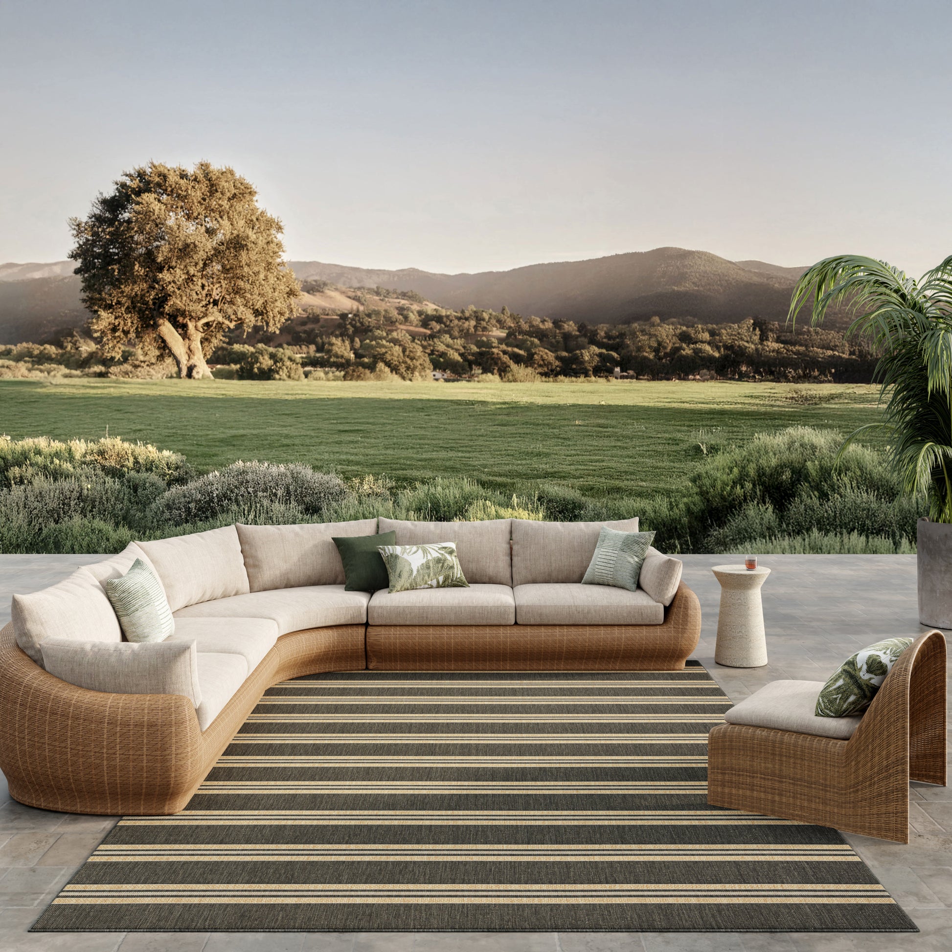 9' x 12' striped rug on a patio with cream cushions and green pillows nearby, overlooking rolling fields and hills.