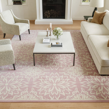 Cozy living room with pink floral rug, white coffee table, cream sofa and chairs, candles and flowers.