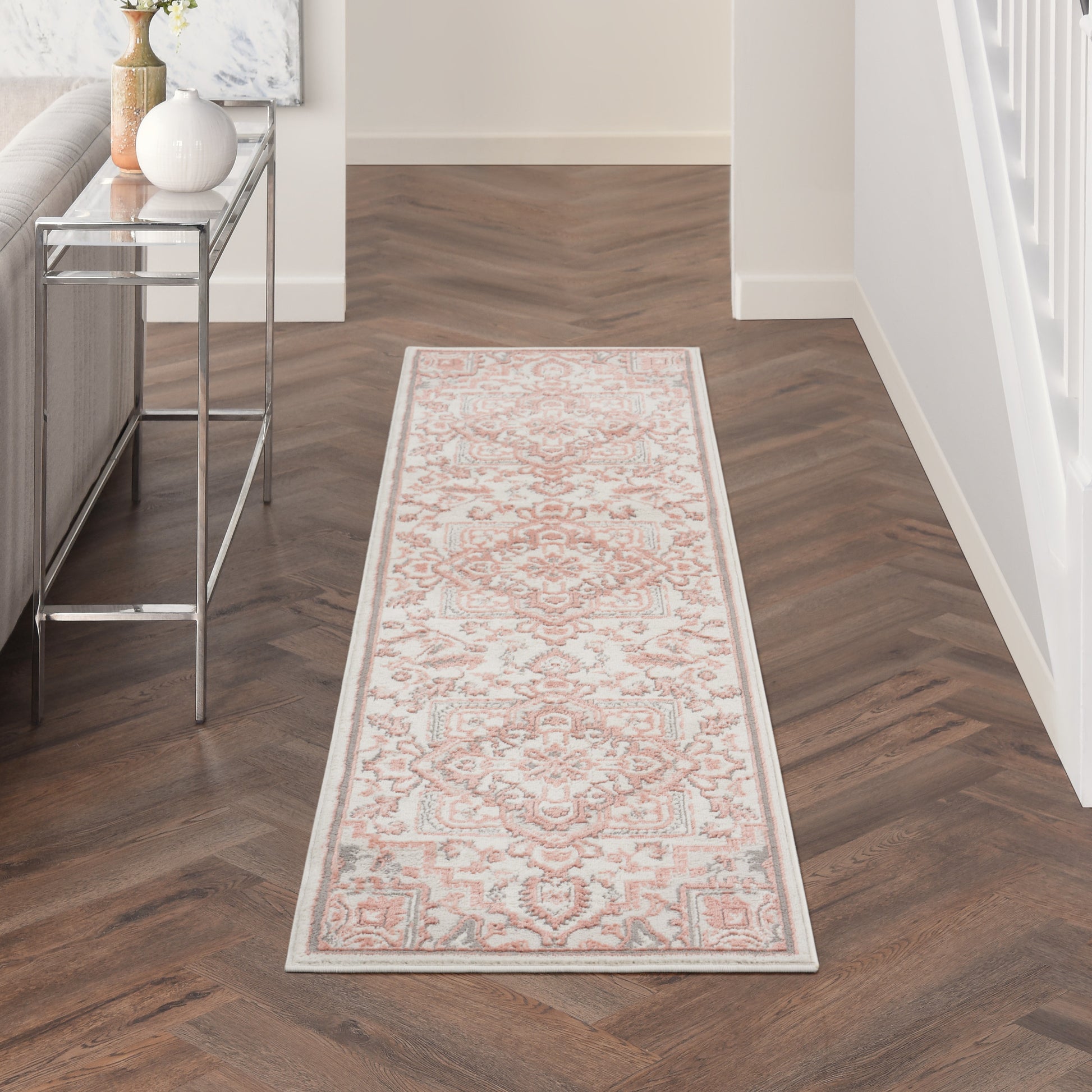 Long runner rug with ivory background and pink floral motif, pale blue border; Persian-inspired hallway decor.