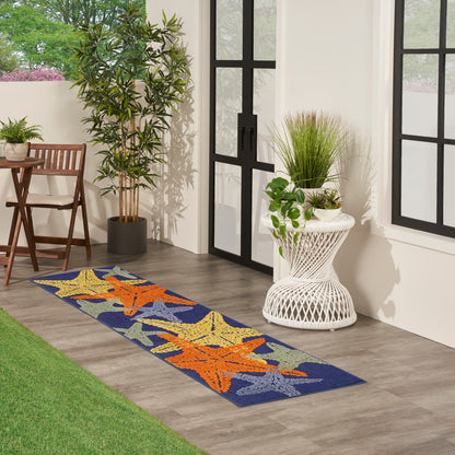 Outdoor patio runner rug with blue background and orange starfish motifs, on wood floor by glass doors.