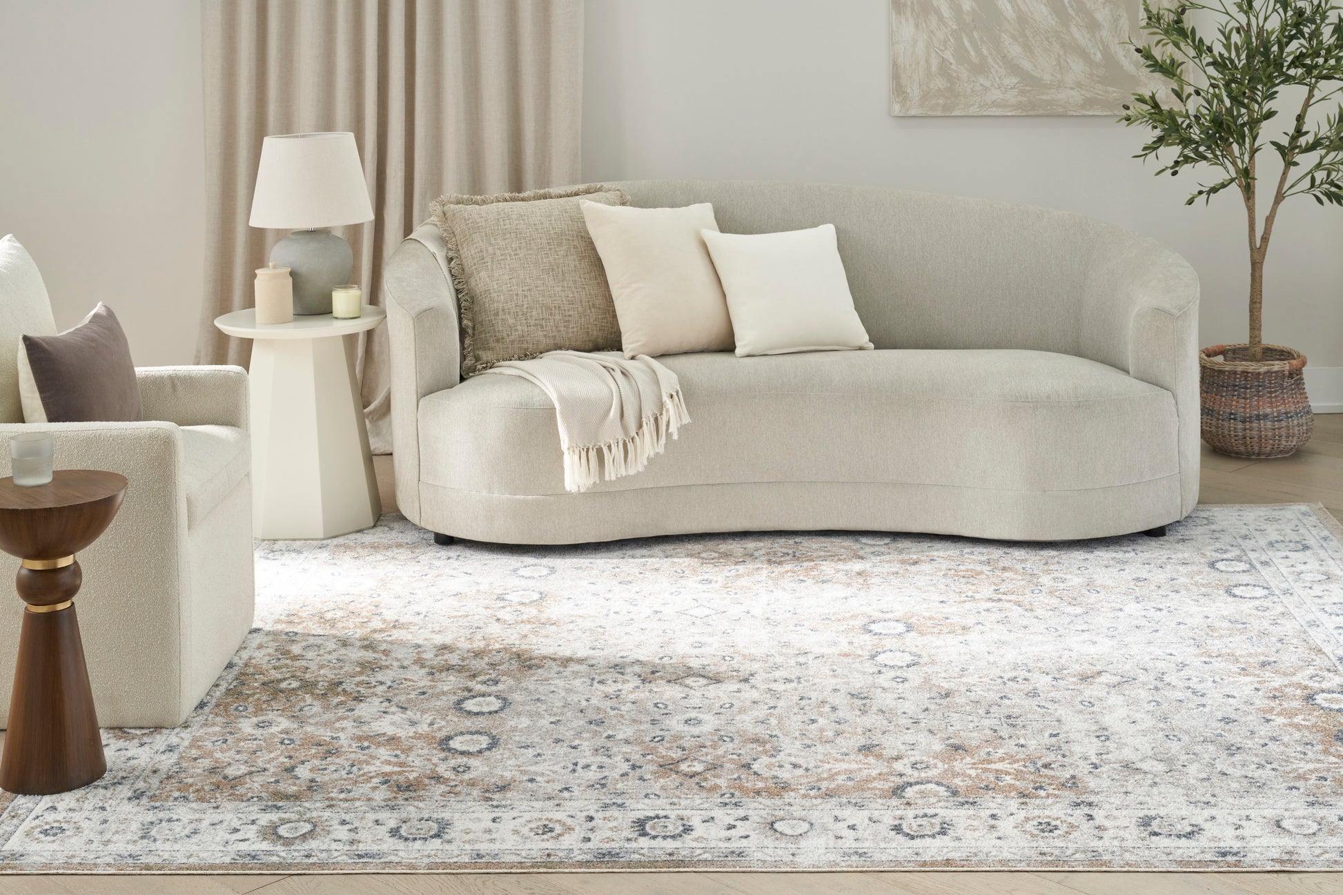 Cream-colored vintage rug (7' x 9') on a neutral living room floor, with a plant and a lamp.