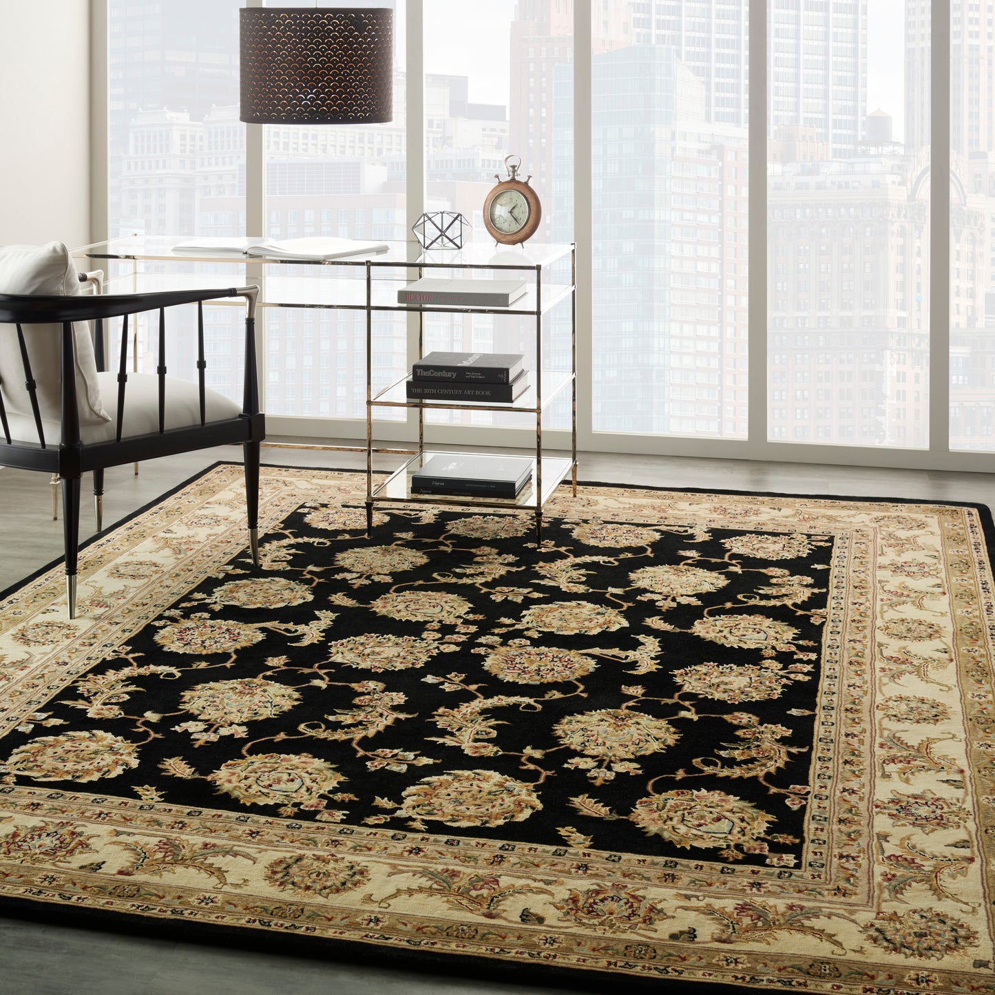 Elegant living room with black-and-gold ornate rug, glass-and-gold console table, black drum lamp, and city view.