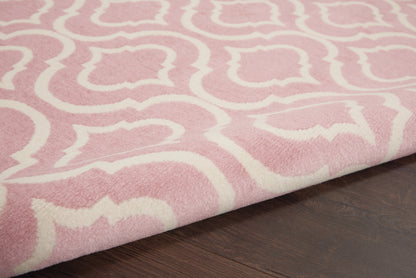 Pink plush rug with white abstract pattern, folded edge on dark wooden floor.