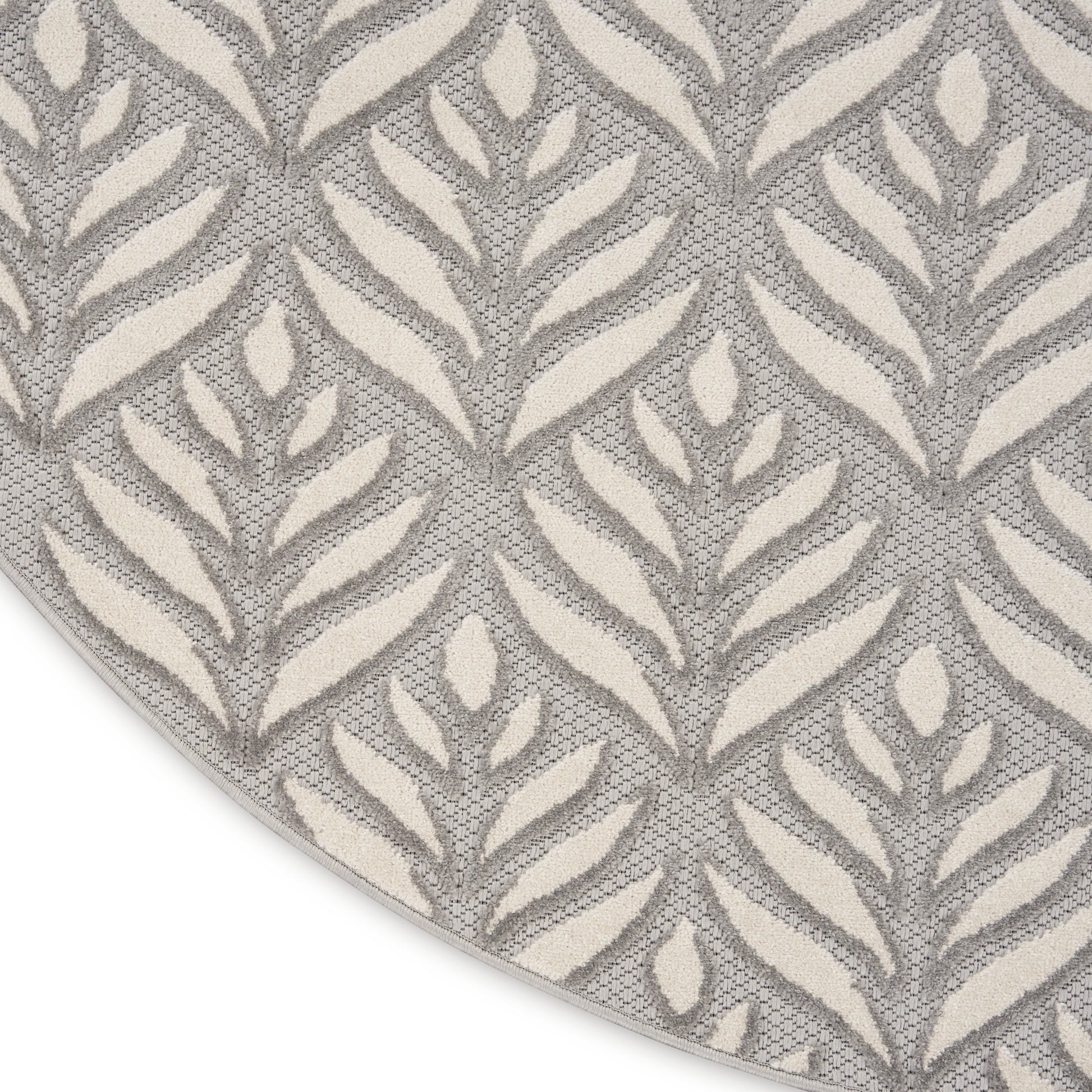 Round rug with ivory leaf motifs on a gray woven background; textured, modern botanical style.
