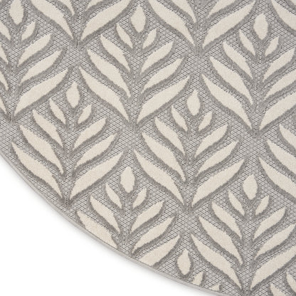 Round rug with ivory leaf motifs on a gray woven background; textured, modern botanical style.