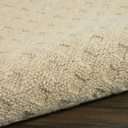 Cream beige shag rug with dense looped pile, plush texture on dark wood flooring.