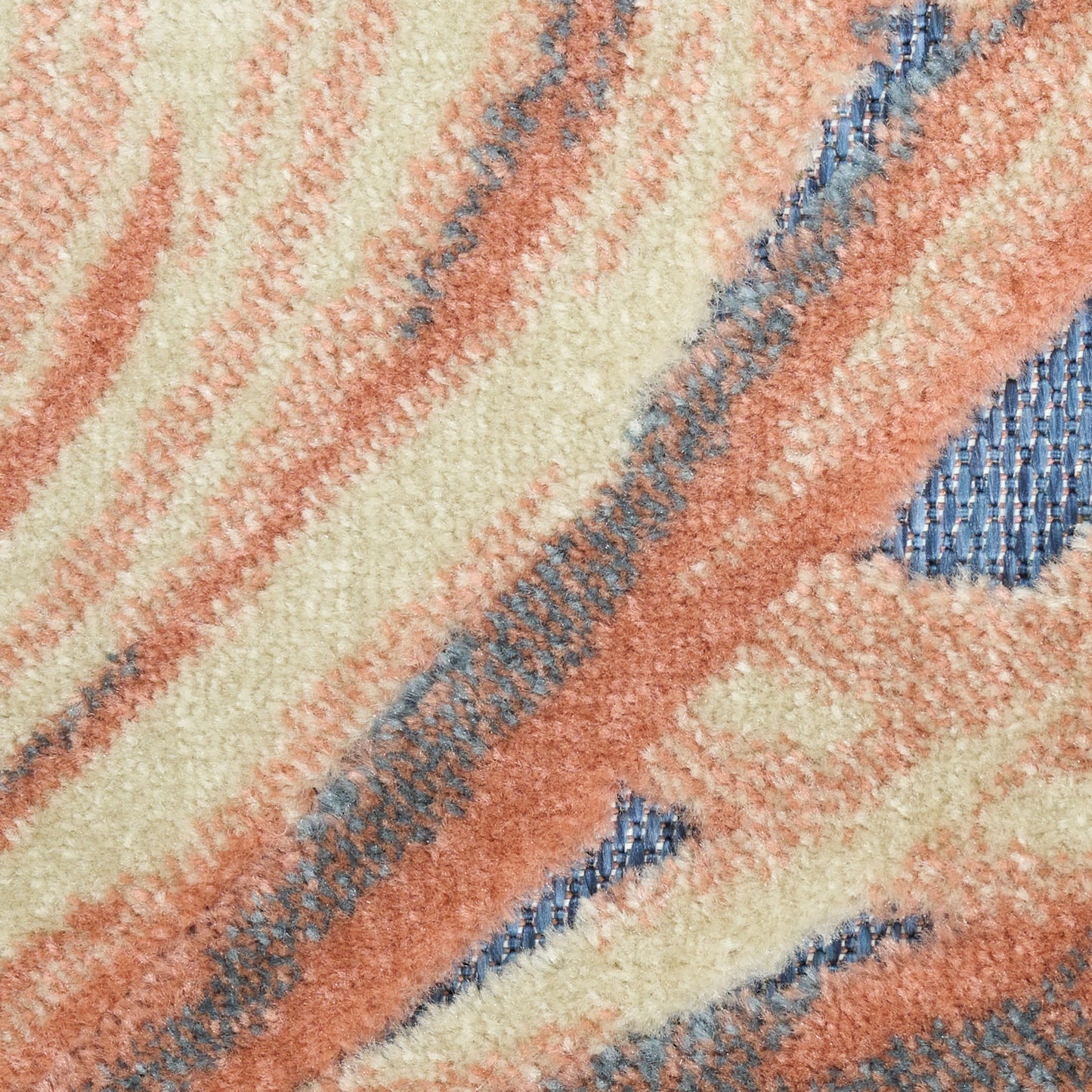 Close-up of a plush rug with peach, cream and blue wavy stripes and a soft shag texture.