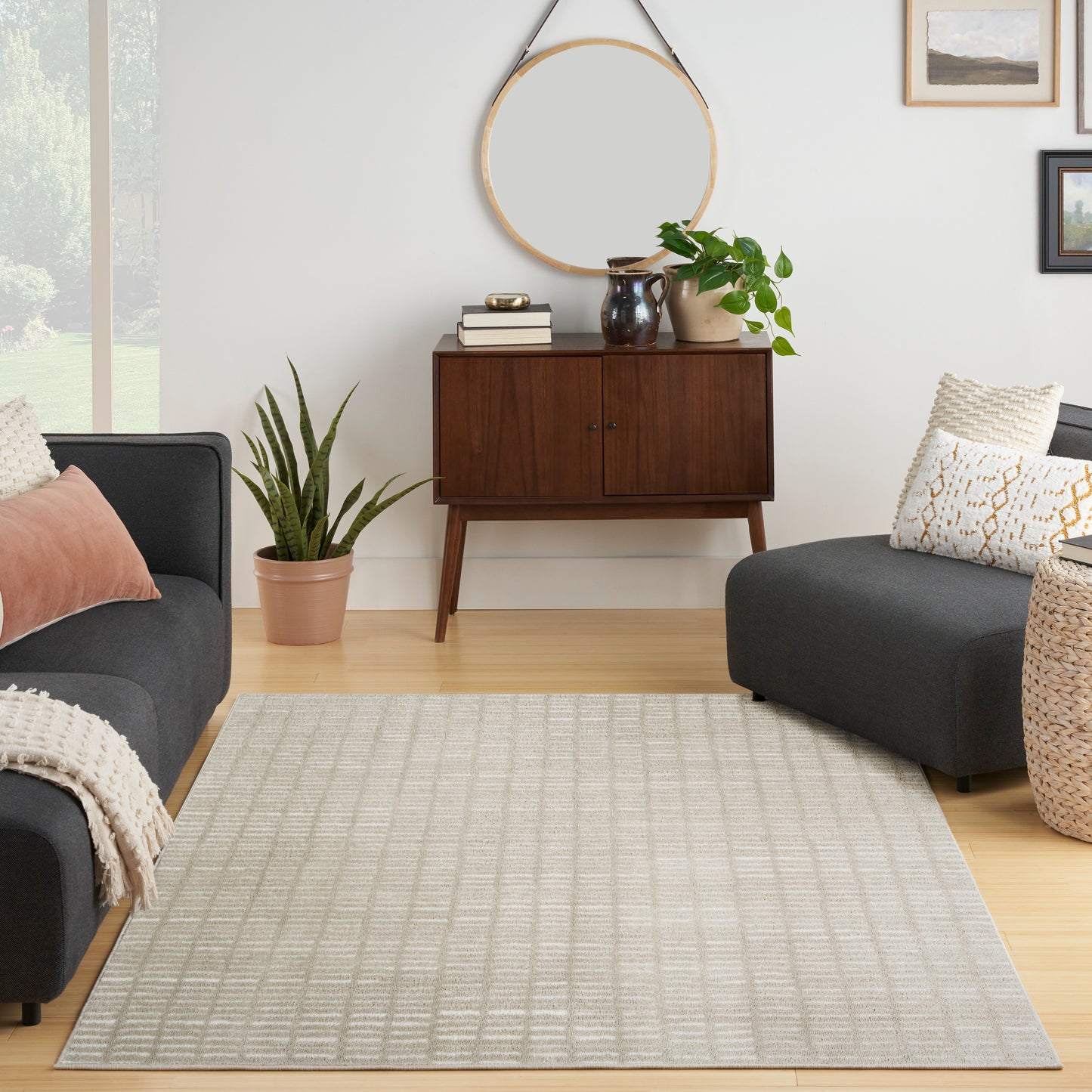 Beige woven area rug with a subtle grid pattern in a neutral living room with gray sofas and a mid-century wood sideboard.