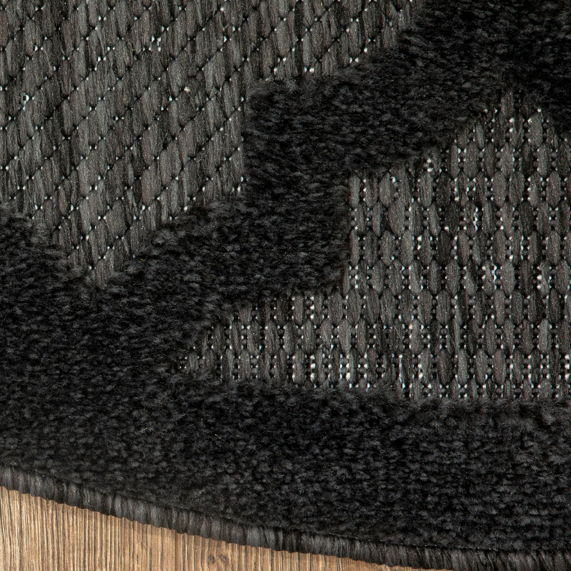 Charcoal gray woven rug with metallic threads and a black plush shag border, close-up.