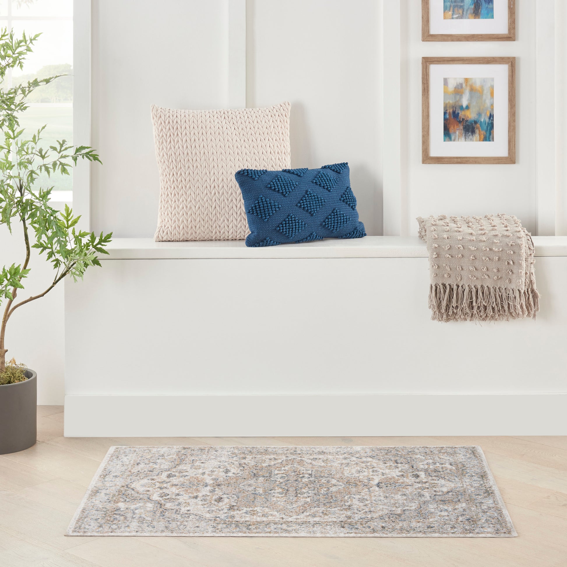Soft grey-blue patterned area rug on light wood floor with beige knit pillow and blue textured pillow.