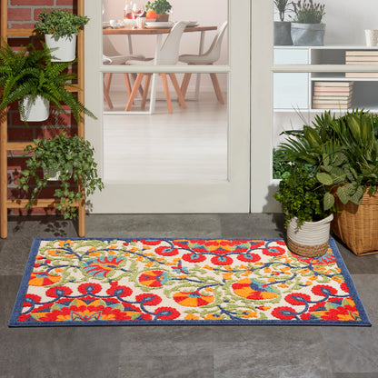 Colorful floral outdoor doormat with blue border at doorway; multicolor red, yellow, green pattern.