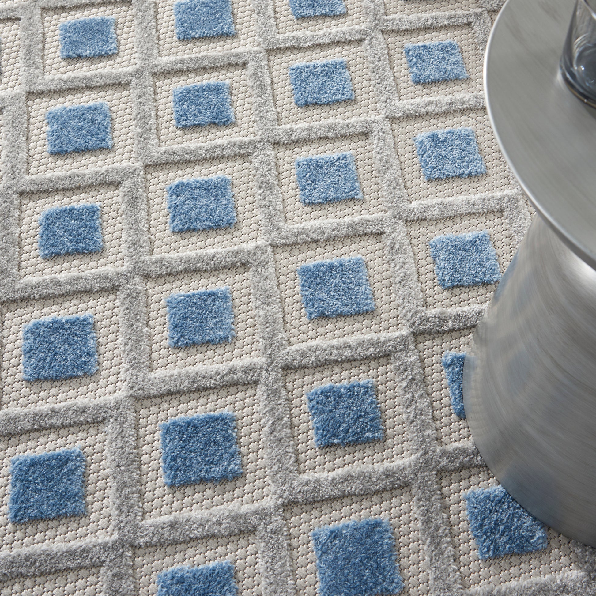 Textured grey round rug with raised blue square centers in a grid; modern geometric design, 4 ft diameter.