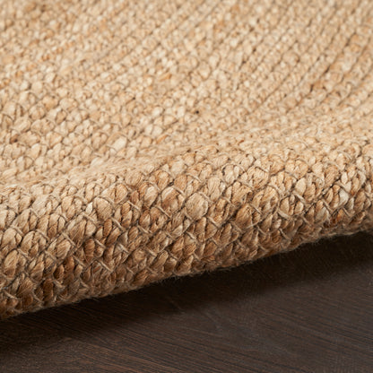 Close-up of natural jute braided 6' runner rug in beige tones with thick twisted fibers and a rolled edge on a dark wood floor.