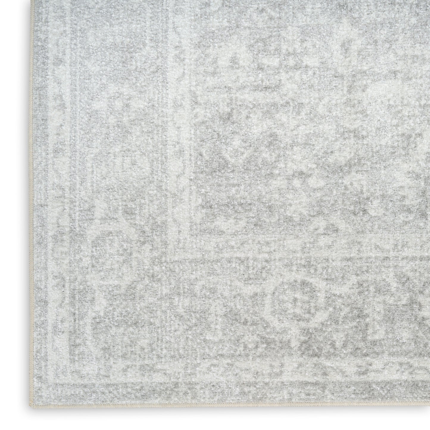 Light gray distressed rug with a subtle oriental pattern and cream fringe along the edge.