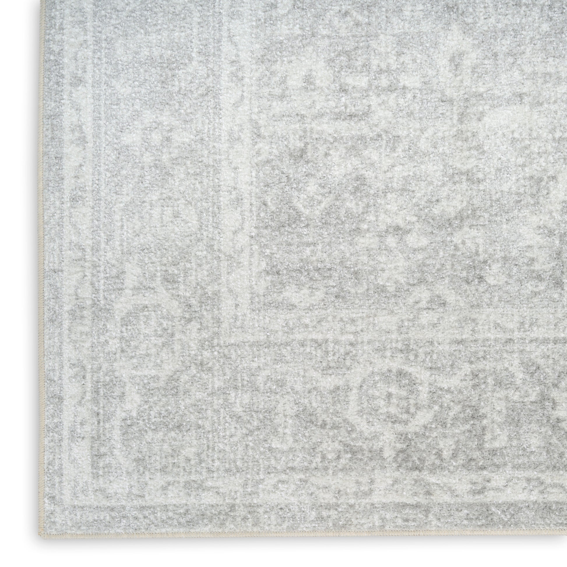 Light gray distressed rug with a subtle oriental pattern and cream fringe along the edge.