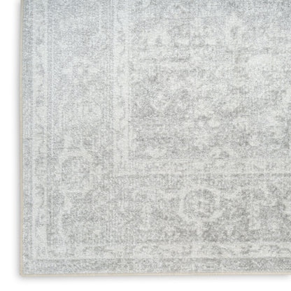 Light gray distressed rug with a subtle oriental pattern and cream fringe along the edge.