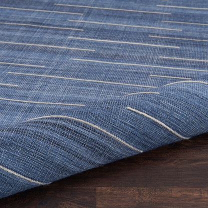 Blue denim-style fabric with white stripe accents, textured weave, draped over dark wood surface.