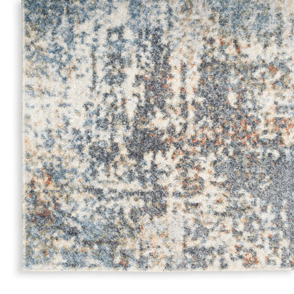 Abstract blue, gray, and beige area rug with a speckled, mottled texture and subtle orange accents.