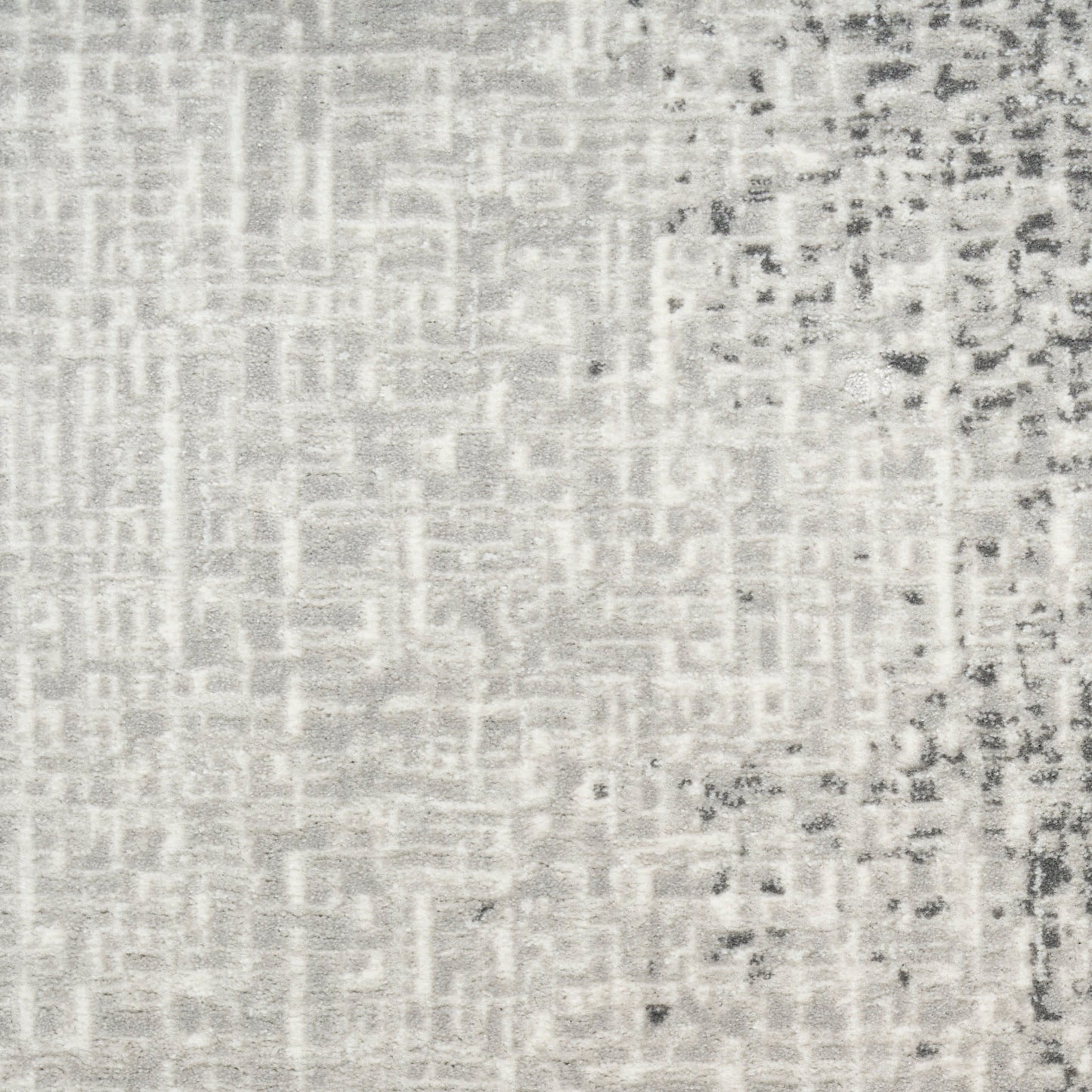 Light gray woven textile close-up with a subtle grid pattern and darker speckled edge on the right.