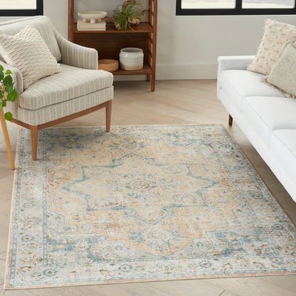 Distressed blue and cream oriental area rug in a bright living room with beige striped armchair and white sofa.