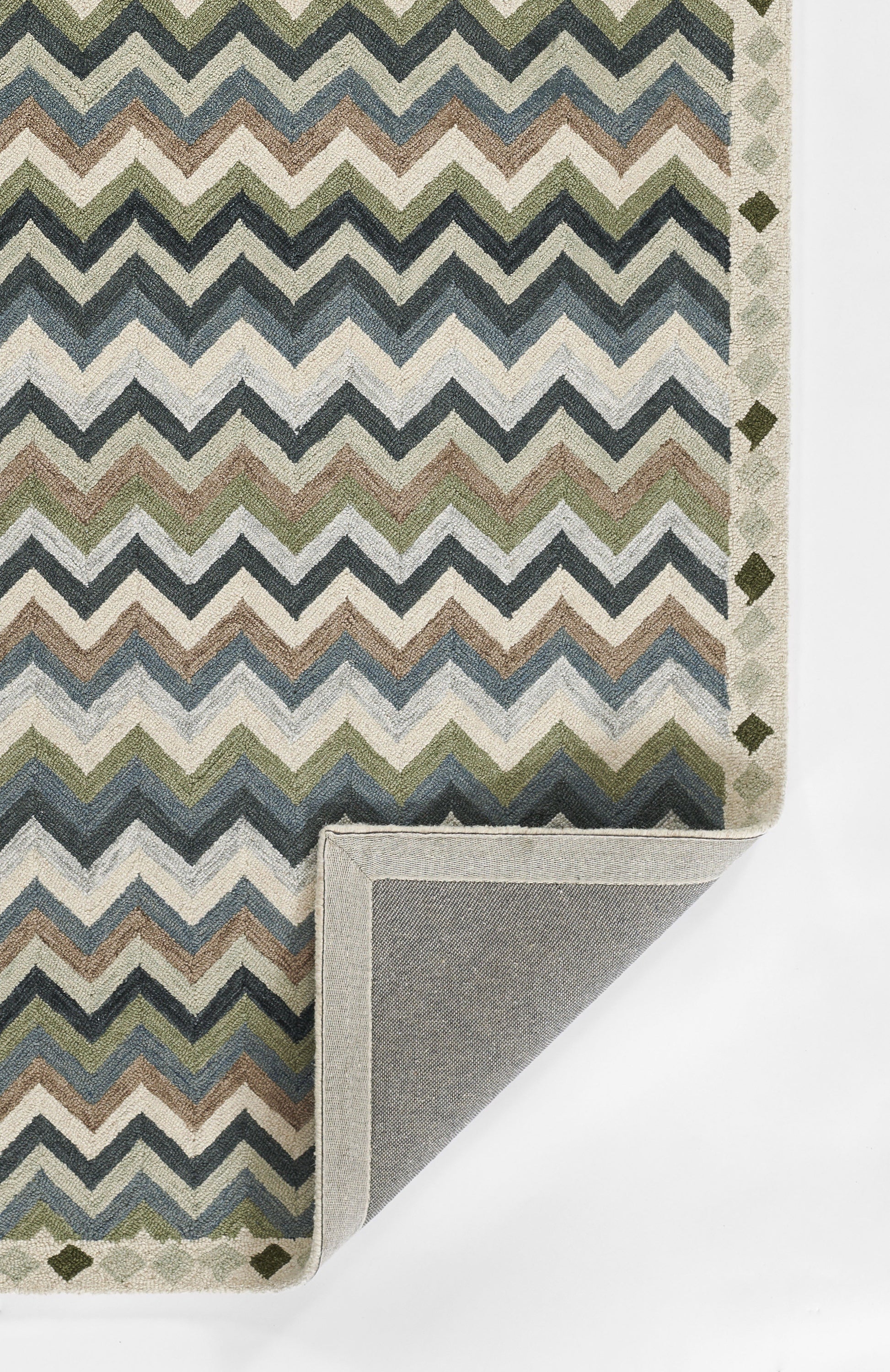 Chevron pattern rug in blues, greens & beiges; folded corner shows gray backing; border features small diamond shapes.