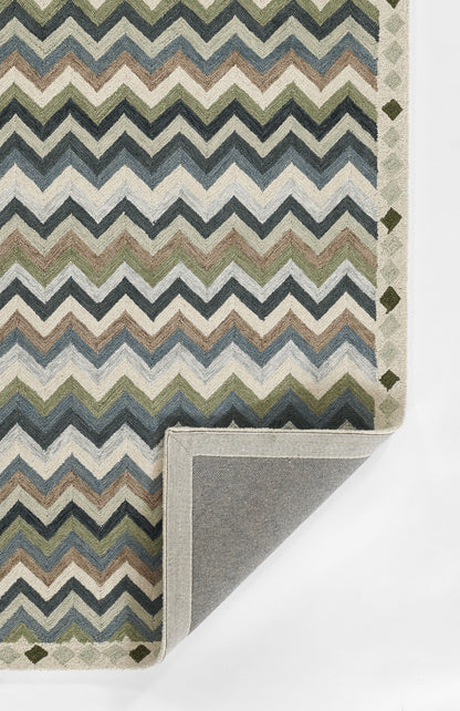 Chevron pattern rug in blues, greens & beiges; folded corner shows gray backing; border features small diamond shapes.
