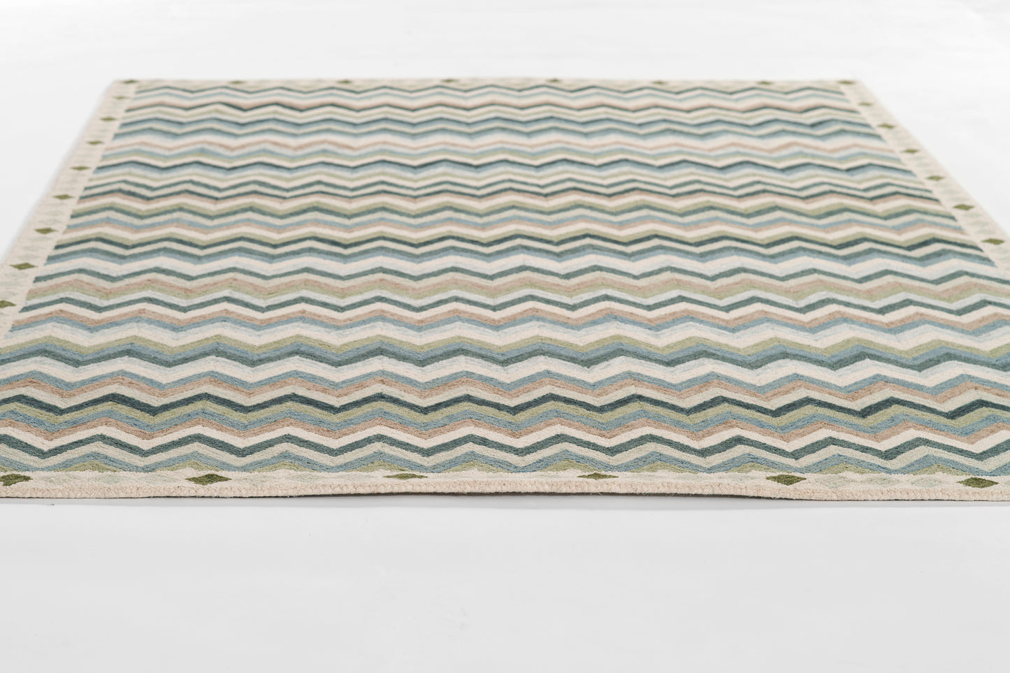 Rectangular flat-weave rug with blue-teal chevron zigzags, beige border and fringe.