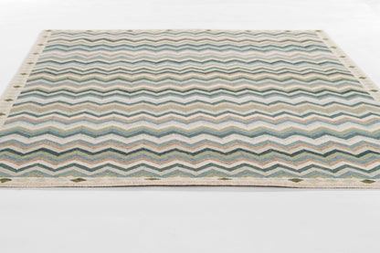 Rectangular flat-weave rug with blue-teal chevron zigzags, beige border and fringe.