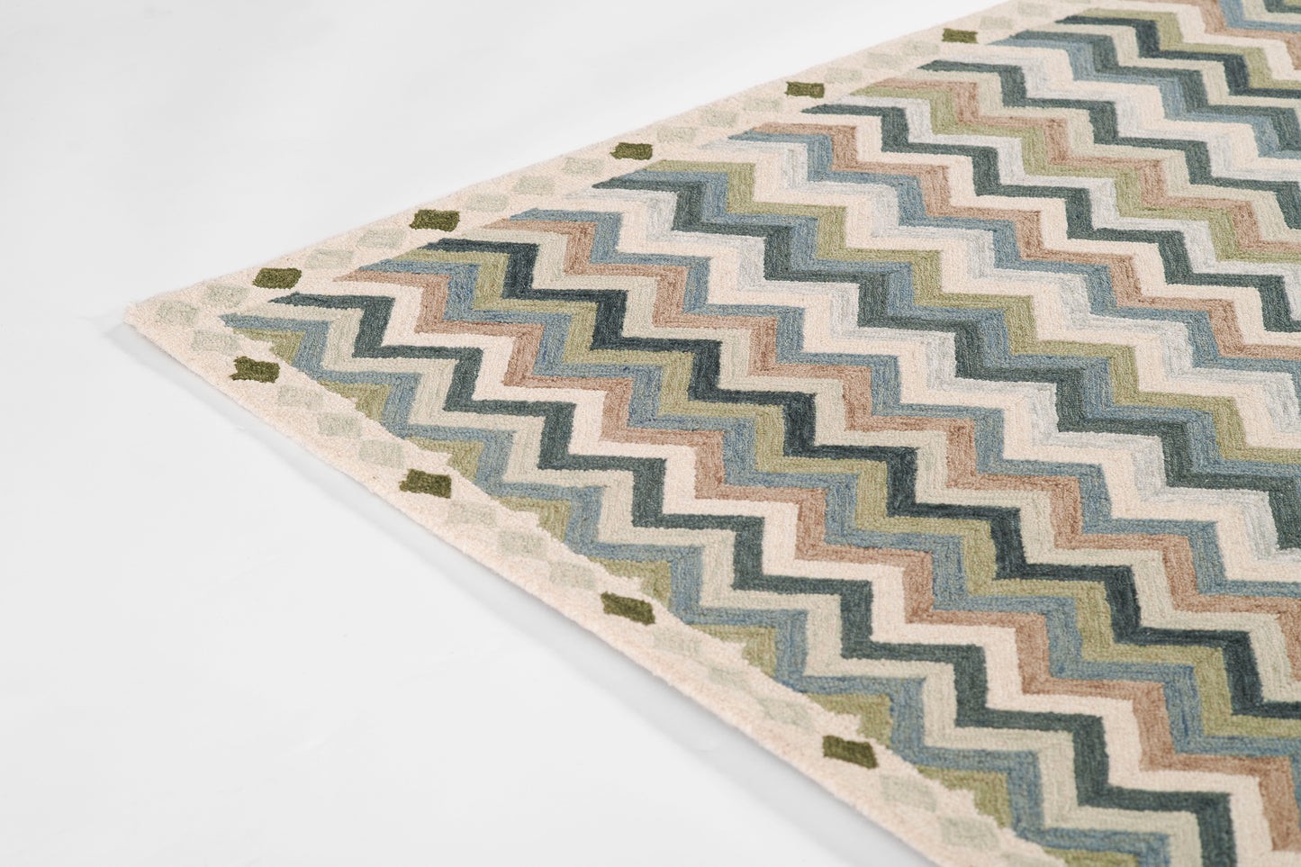 Chevron-pattern rug in blues, greens, and creams with beige border; flat-woven textile for living room decor.