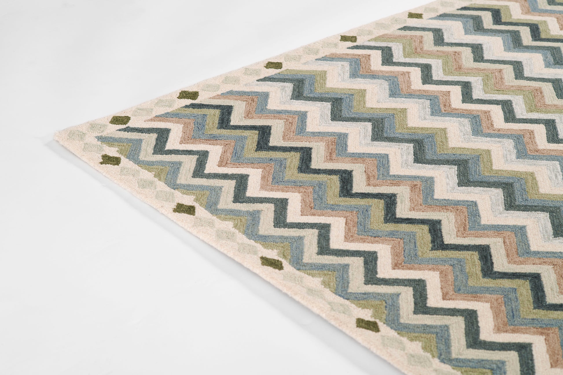 Chevron-pattern rug in blues, greens, and creams with beige border; flat-woven textile for living room decor.