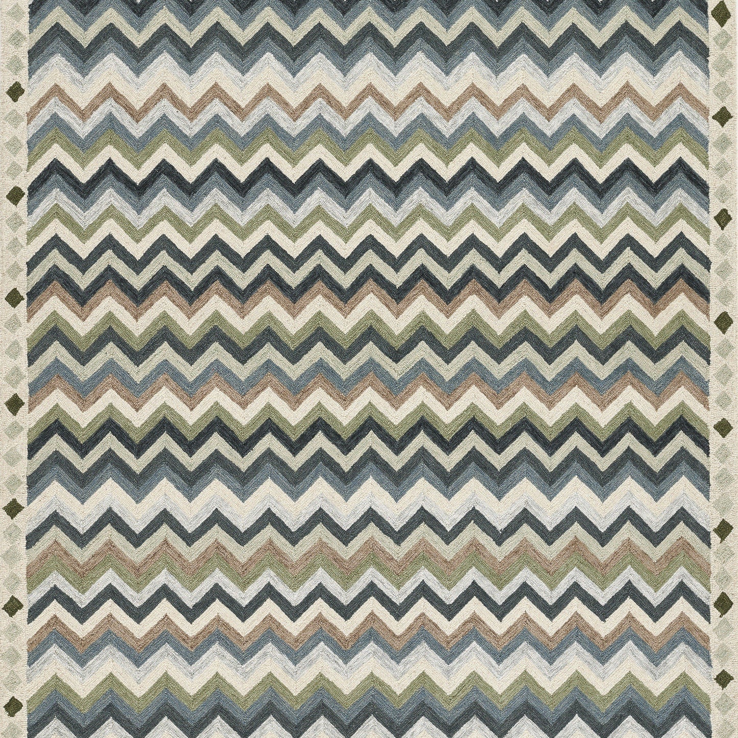 Chevron-pattern rug in blue, green, and ivory tones with zigzag stripes on a neutral floor.