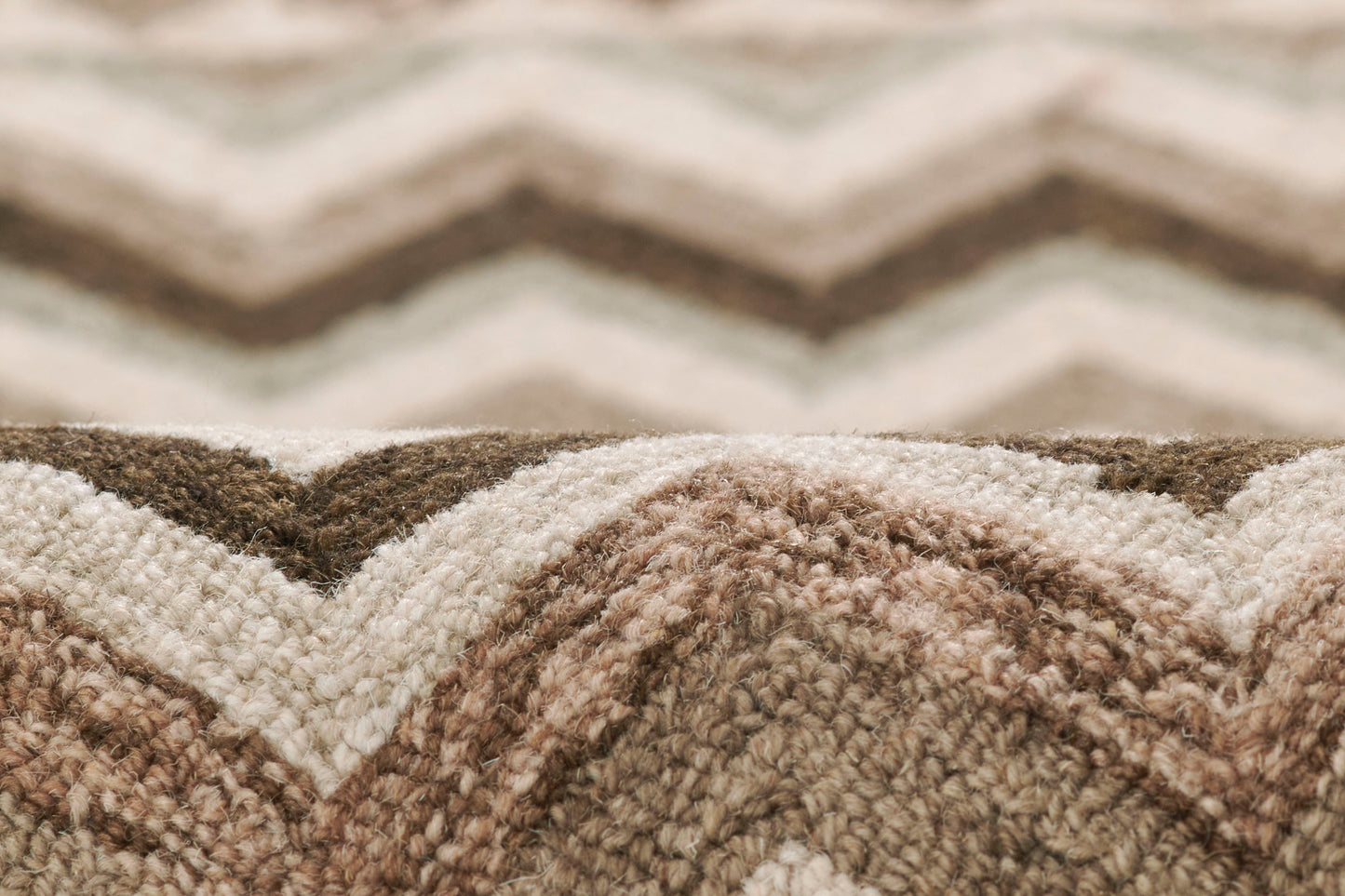 Close-up of a beige-brown chevron woven rug with soft plush pile and neutral tones.