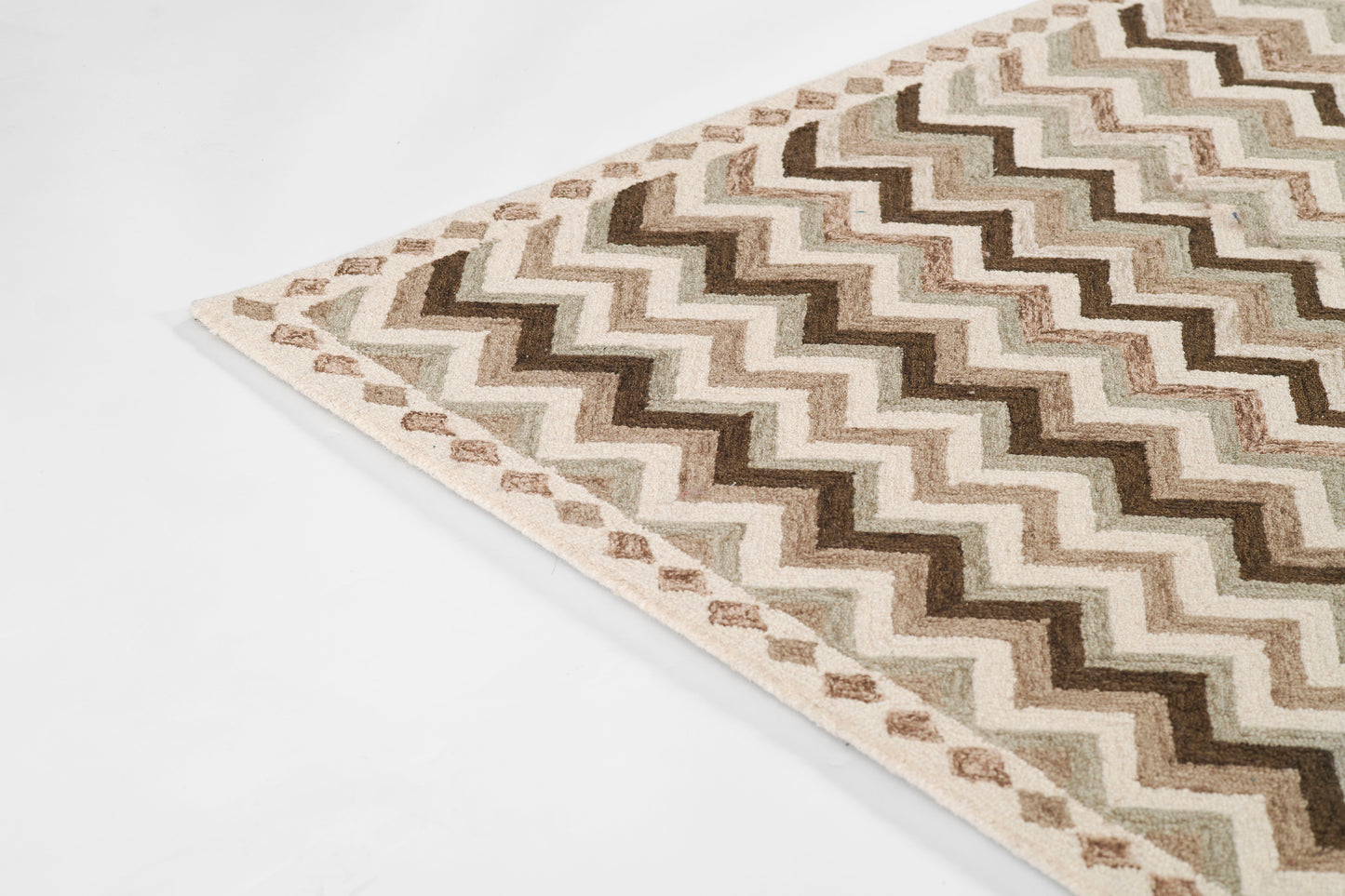 Rectangular woven rug with beige, tan and brown chevron pattern; subtle diamond border along edges.