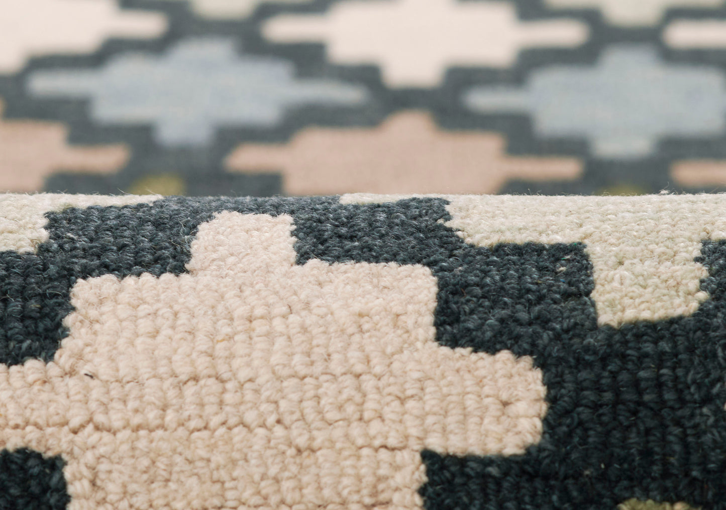 Close-up of a geometric-pattern rug with cream, navy and light blue blocks; thick tufted pile in a modern kilim-inspired look