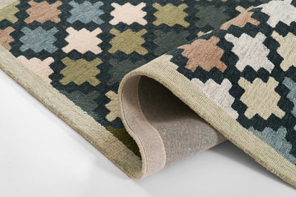 Geometric diamond trellis rug in navy, beige, peach and olive; flat-weave with rolled edge and light tan backing.