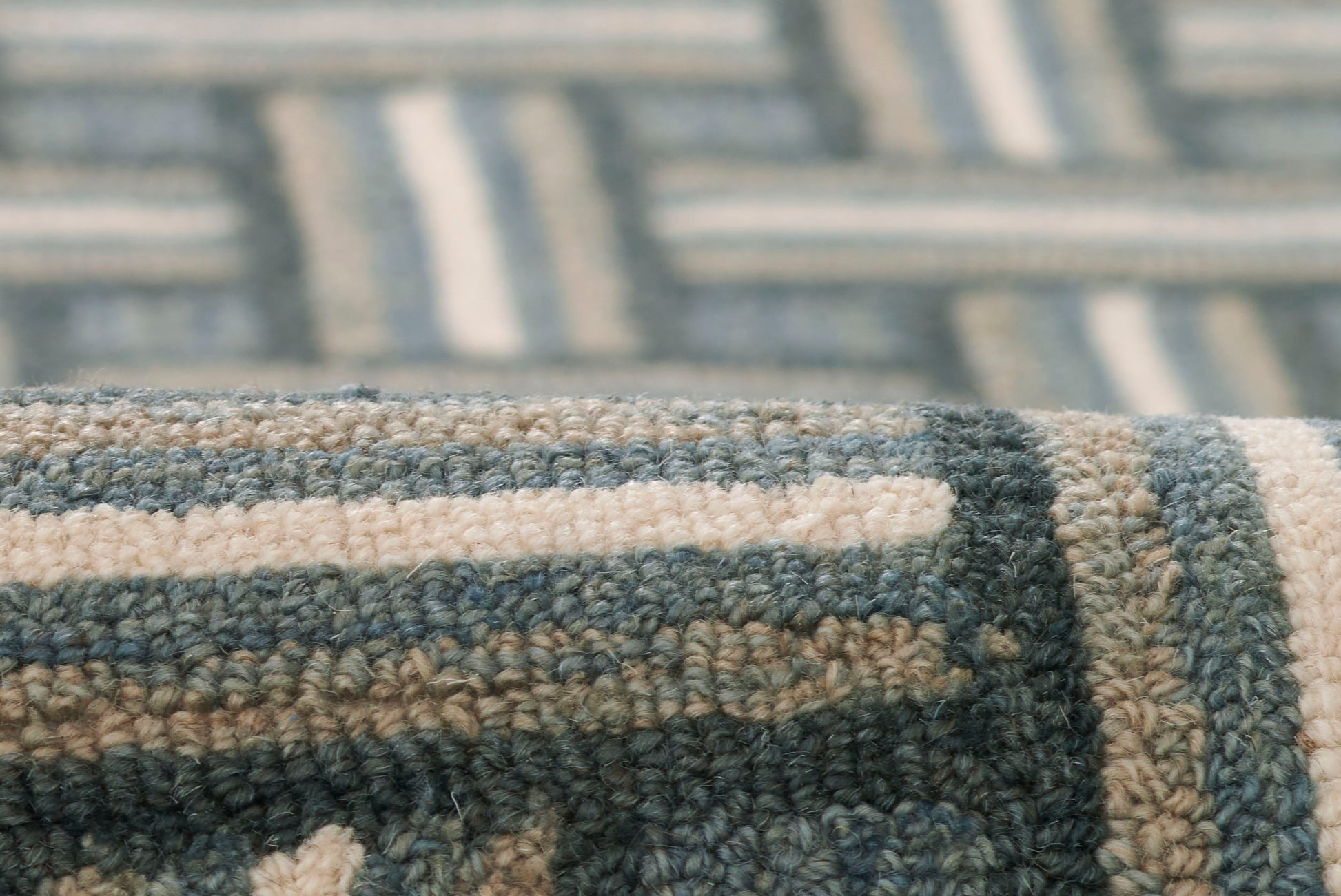 Close-up of a blue and beige geometric woven rug with cream stripes and textured pile.