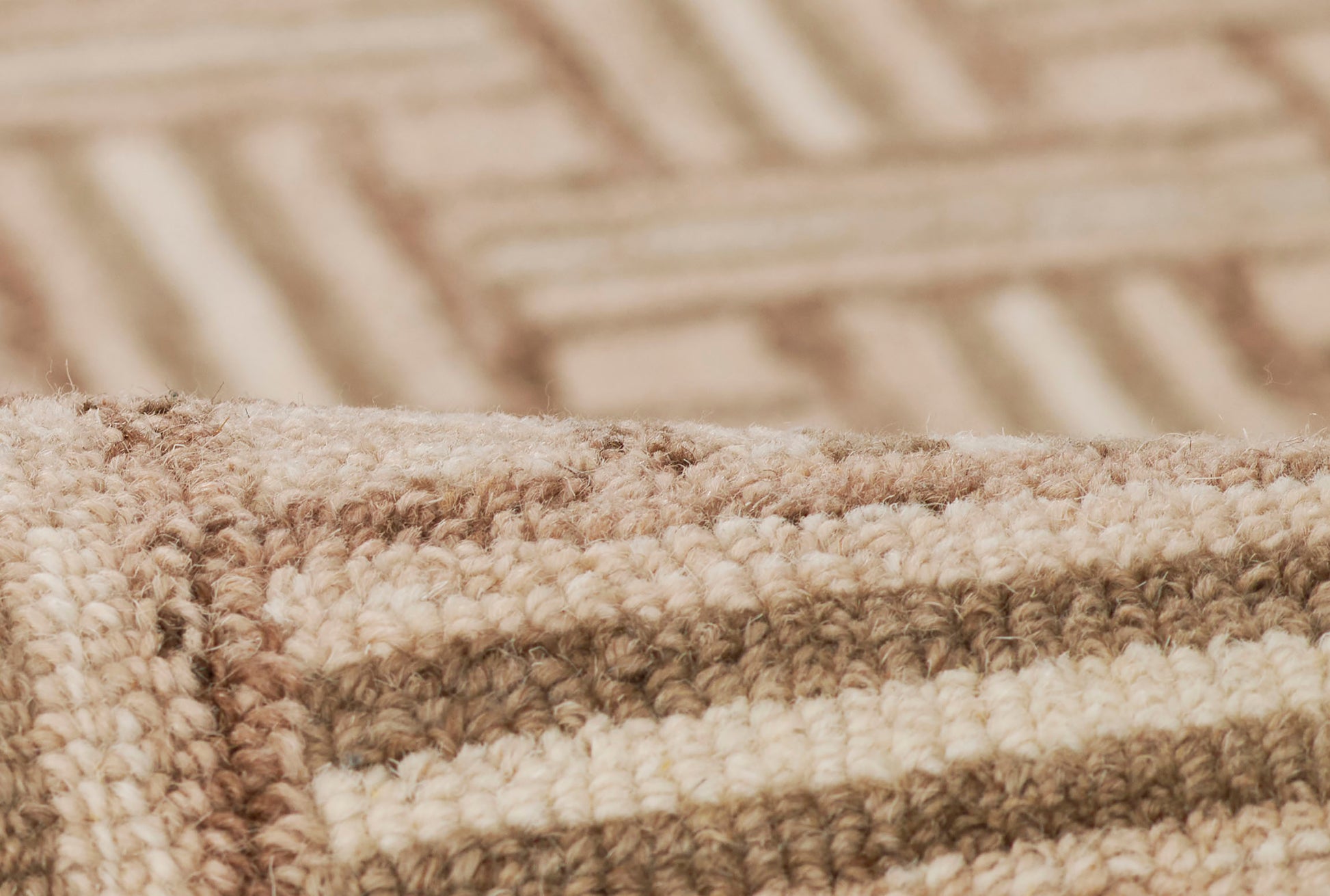 Close-up of a beige, taupe and light-brown striped woven rug edge with soft tufted pile.