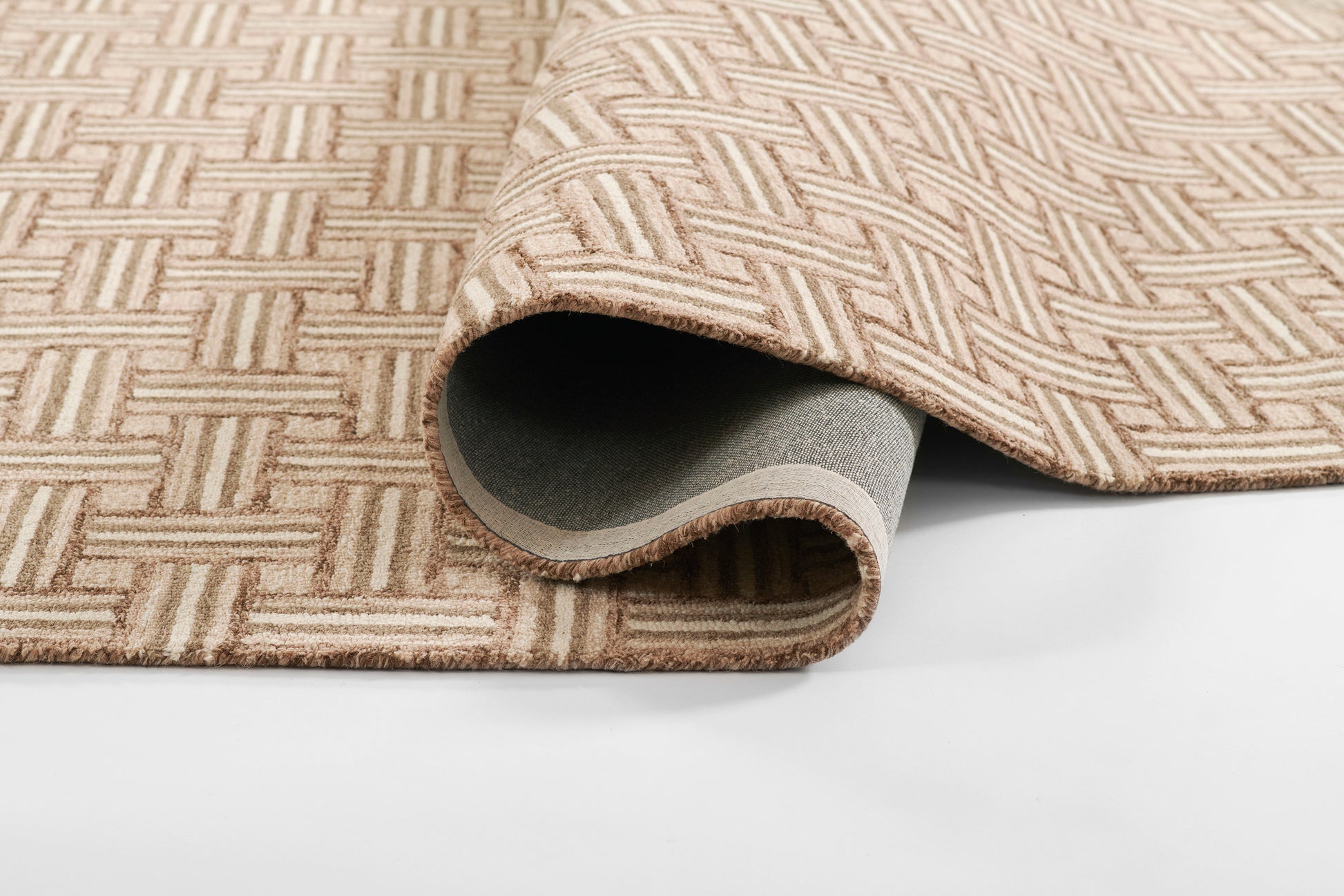 Beige woven rug with a square lattice geometric pattern, partially rolled to reveal the soft underside.