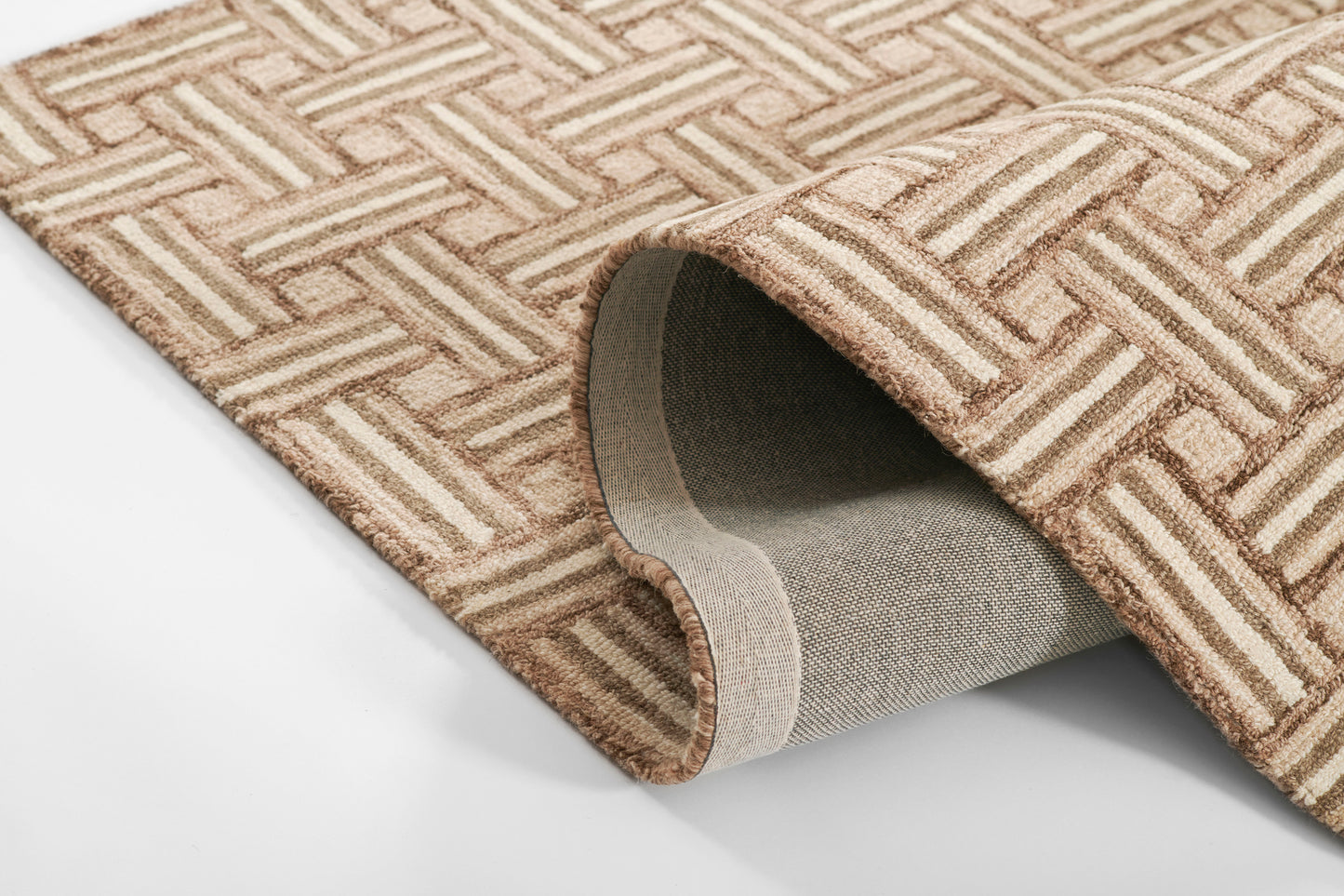 Beige and tan geometric lattice woven rug with a curled edge, gray underside exposed.