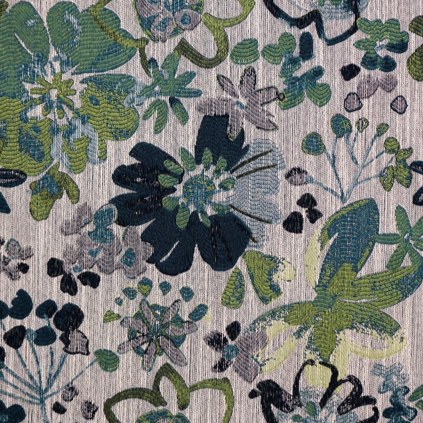Floral printed woven fabric in blue, teal, and green with leafy motifs on a light beige background.